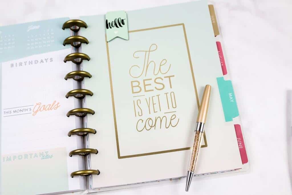 Hello the best is yet to come quote in a journal with a gold pen.