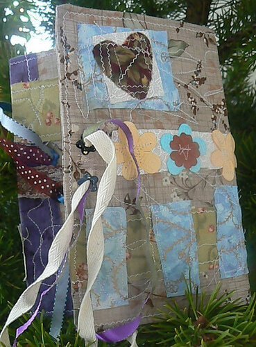 A fabric journal with sewn flowers and ribbons.