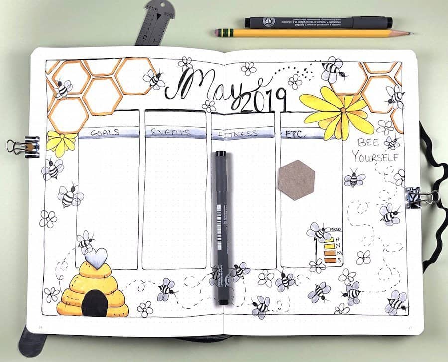 A bullet journal spread for May with bumble bees and flowers.