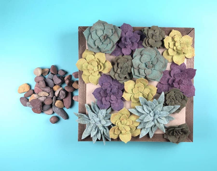 Felt succulent wall art with pebbles.