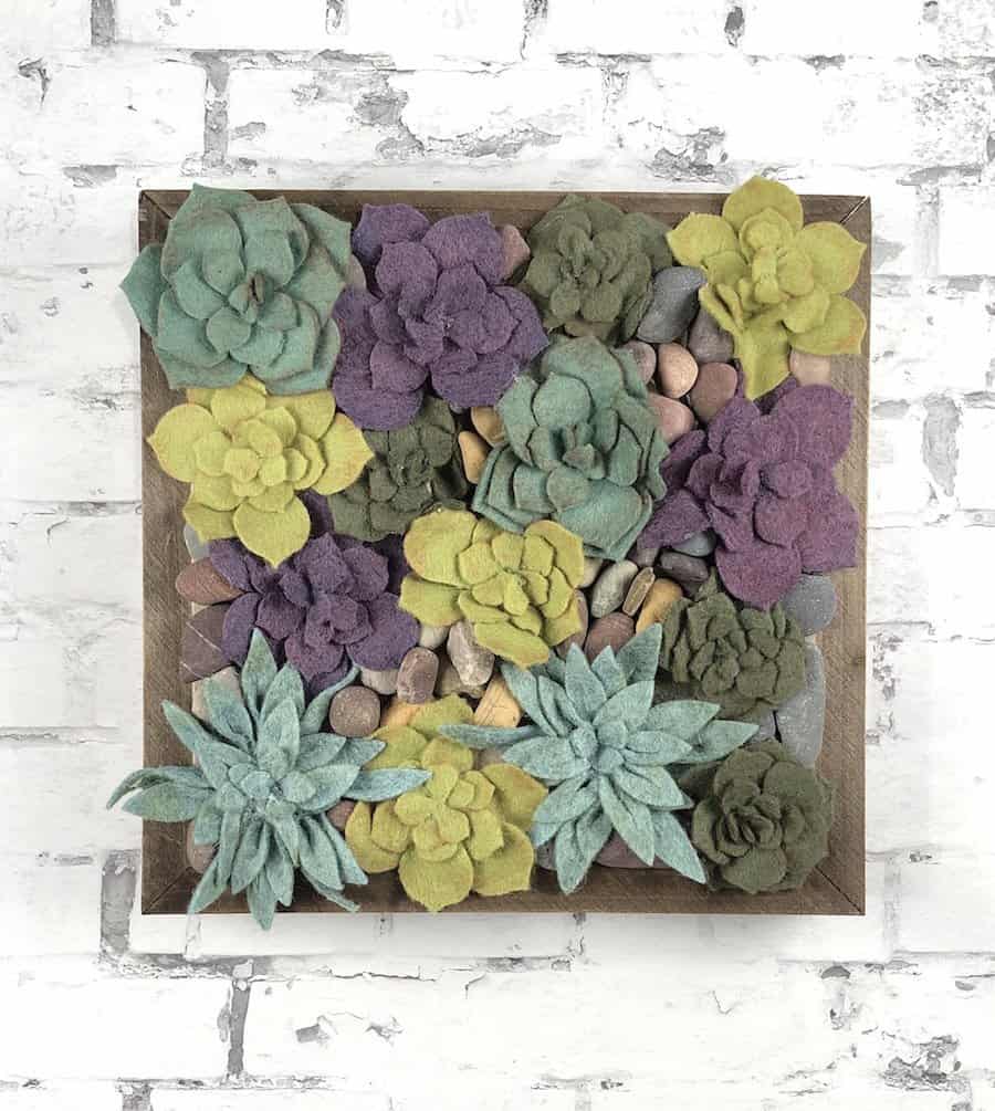 Felt succulent wall art with purples, greens, and pebbles.